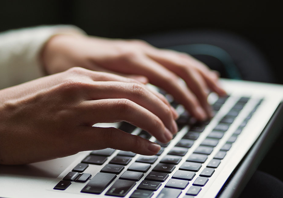 A closeup of a person typing on a laptop keyboard.